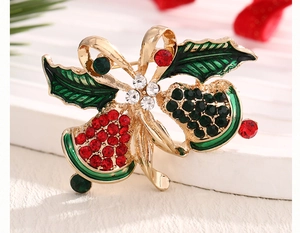 Macro shot of Christmas bell brooch with red and green rhinestones and bow detail