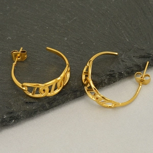 Detail of gold chain link earrings on dark rock texture and beige fabric background