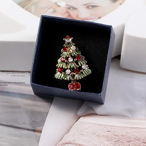 Close-up of a festive Christmas tree brooch with red rhinestones in a blue gift box