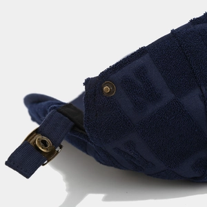 Detail of navy blue textured fabric with H embossing and vintage bronze metal buckle