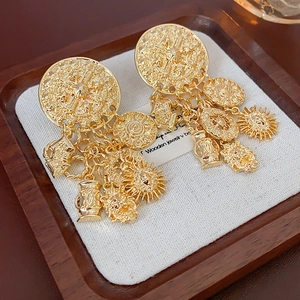 Detailansicht goldener Vintage-Ohrringe mit Sonnen- und Löwen-Anhängern auf Tablett