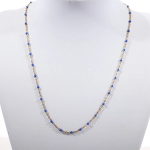 Detail of bohemian gold beaded chain with vibrant blue enamel charms on a white display