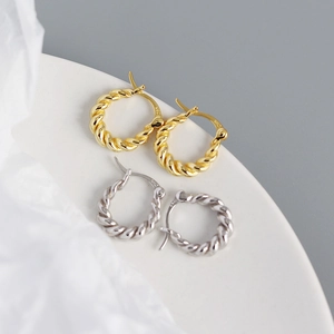 Macro detail of twisted rope hoop earrings in gold and S925 sterling silver finishes