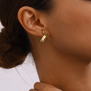 Close-up of a model wearing a gold bird-shaped stainless steel earring with metallic luster