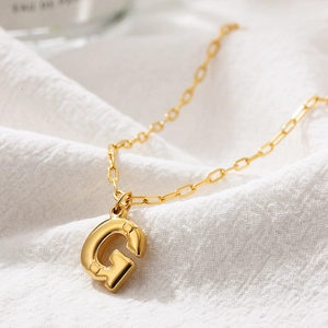 Detail of 3D bubble letter G pendant in gold stainless steel on a paperclip chain