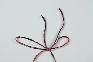 Gros plan sur le tissu en mesh à imprimé abstrait rouge et rose noué en nœud