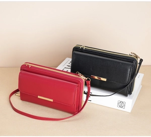 Detail of red and black leather crossbody wallets with gold zippers and metal bar accent