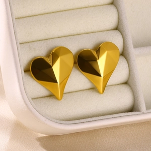Macro shot of gold heart-shaped stud earrings with textured finish in a jewelry box