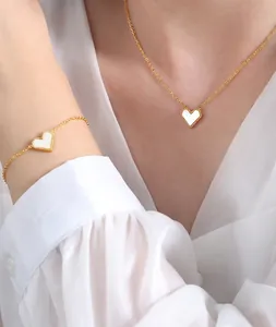 Detail of 18K gold plated necklace and bracelet set featuring white shell heart charms