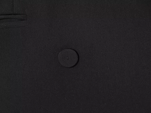 Dettaglio ravvicinato di tessuto twill nero con bottone foderato e bordo della tasca