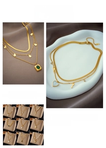 Close-up of layered gold necklaces with emerald pendant and pearl heart details