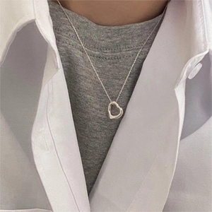 Detailed view of an open heart pendant necklace on a silver chain worn by a model