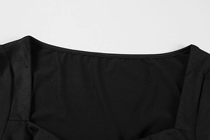 Detail des quadratischen Ausschnitts und Metall-Dekors an einem schwarzen Kleid