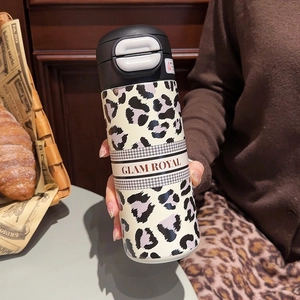 Detail of leopard print thermos with GLAM ROYAL strap and houndstooth pattern edges