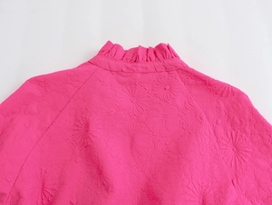 Close-up of rose red embossed floral texture fabric with elegant ruffle stand collar