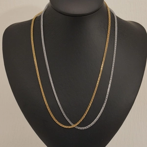 Minimalist stainless steel wheat chain necklaces in gold and silver on a black bust display