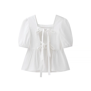 Détail du dos ouvert du haut blanc à manches bouffantes avec nœuds papillon décoratifs