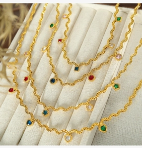 Detail of gold necklaces with colorful zircon stones and wave textured chains