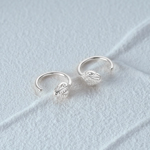 Macro shot of silver snake head earrings featuring detailed texture and polished finish