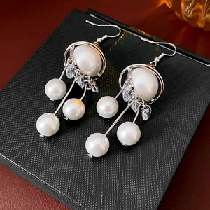 Detail of planet-style pearl tassel earrings with zircons on a jewelry box cover