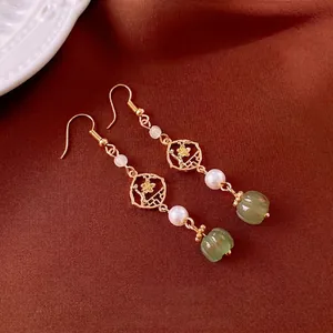 Retro Chinese style flower earrings with pearls and green jade beads on brown fabric