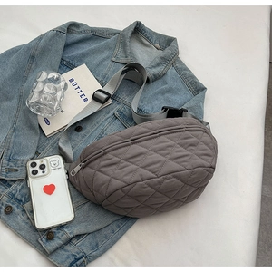 Detailed view of gray quilted crossbody bag on denim jacket with lifestyle accessories