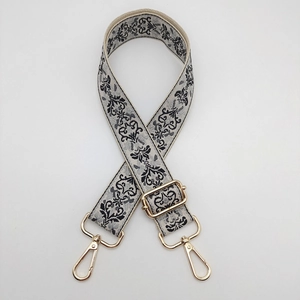 Close-up of black and grey jacquard bag strap with adjustable golden metal hardware