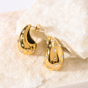 Polished gold teardrop hollow earrings with scattered white diamonds on a stone background
