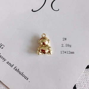 Macro shot of 17x12mm golden hollow bear charm holding a heart on white card background