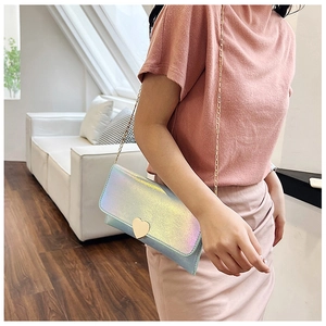Detail of holographic mini bag featuring a gold heart clasp and elegant metal chain strap
