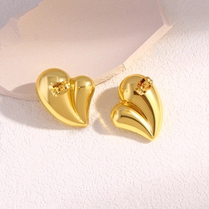 Polished 18K gold heart stud earrings shown on a neutral stone background