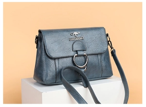 Detail of blue PU leather shoulder bag featuring round silver buckle and kangaroo logo