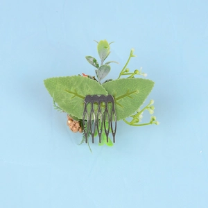 Detail of the metal hair comb teeth on a handmade bridal floral headpiece with green leaves