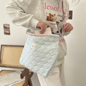 Sac cabas matelassé bleu clair avec bandoulière rose montrant l'intérieur et l'étiquette