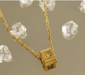 Macro detail of 18k gold plated cube pendant with a square zircon on a reflective base