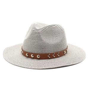 Detail of grey straw hat featuring a brown leather band with silver metal studs