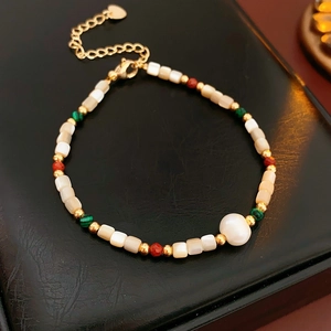 Gros plan d'un bracelet doré avec perle baroque et breloque cœur sur fond en cuir texturé