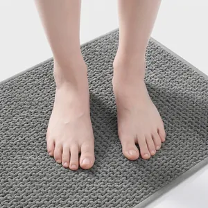 Close-up of bare feet on a thick, soft dark grey chenille absorbent bath mat texture