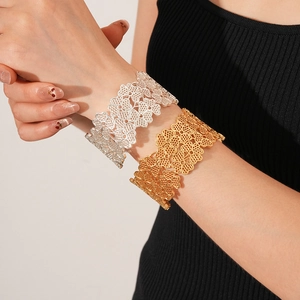 Detailed view of silver and gold wide openwork flower cuffs worn on a wrist