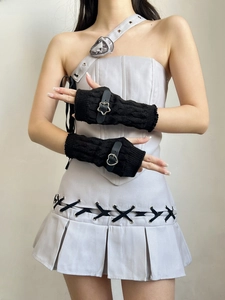 Detail of black cable-knit fingerless gloves featuring star and heart leather buckle straps