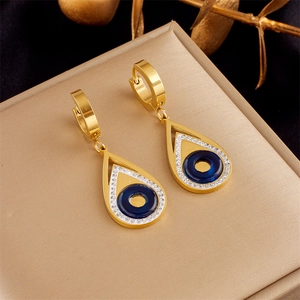 Macro detail of gold teardrop earrings with blue evil eye and sparkling white zircons
