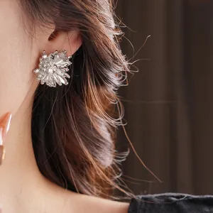 Exquisite silver flower stud earring with central crystal on female model ear
