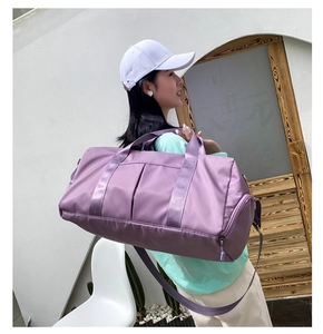 Purple large capacity travel bag worn over the shoulder by a model for yoga and gym use
