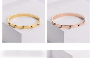 Detail of gold and rose gold stainless steel bangles with studded conical rivets