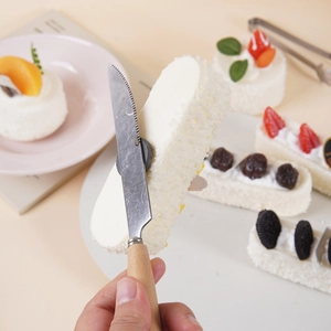 Serrated stainless steel cake knife with wooden handle slicing soft cream dessert