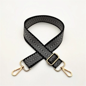Close-up of adjustable bag strap with black and white chevron pattern and gold metal hardware