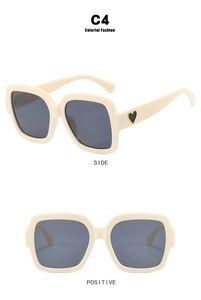 Detailansicht der cremefarbenen Oversize-Sonnenbrille mit goldumrandeten Herzakzenten