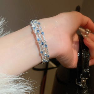 Detail of a three-row silver bracelet featuring sparkling white and deep blue zircon stones