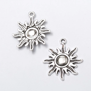 Macro shot of two vintage silver sun-shaped alloy pendants for DIY jewelry making crafts