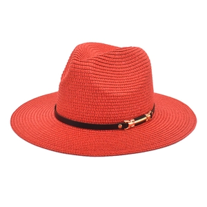 Detail of red straw fedora hat featuring fine weaving texture and black belt with gold buckle